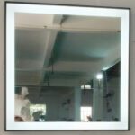 A person is standing in front of a mirror in a room.