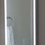 A bathroom sink with a lighted mirror above it.